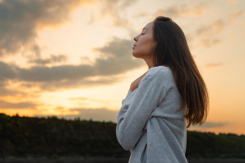 Woman gazes up at vast sky, symbolizing introspection and seeking meaning.