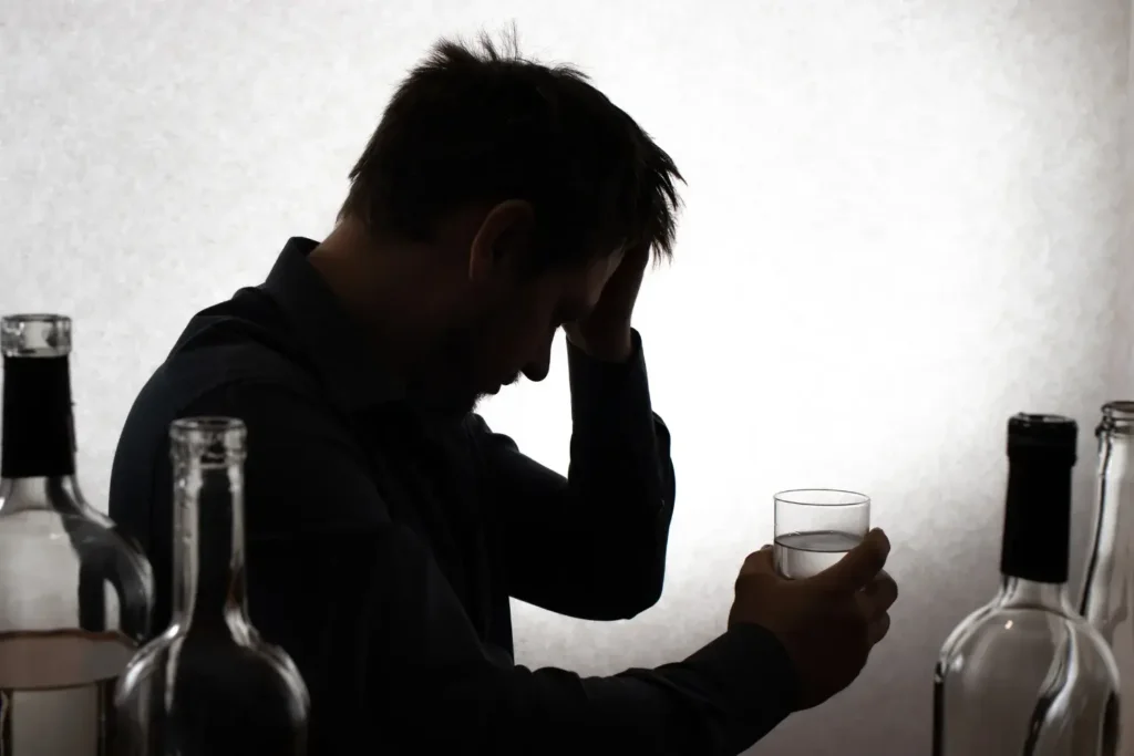 Sad man drinking alcohol, illustrating the struggle with addiction as a coping mechanism for past trauma.