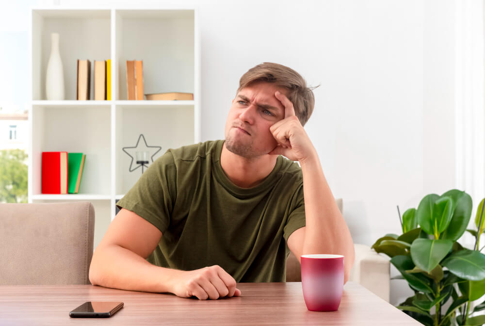 Person sitting quietly on a couch looking anxious instead of relaxed, illustrating how rest can feel uncomfortable due to stress, guilt, or survival mode.